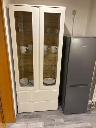 een witte kast met servies erin naast een koelkast bij Top location central in Rüsselsheim