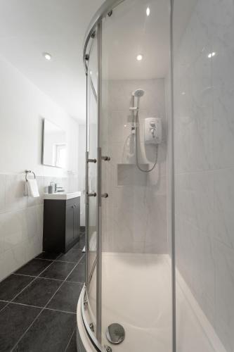 a white bathroom with a shower and a sink at Mayflower Penthouse in Dartmouth