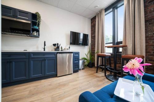 a living room with a blue couch and a kitchen at Blue Room @ The MillRows Suites in New Glasgow