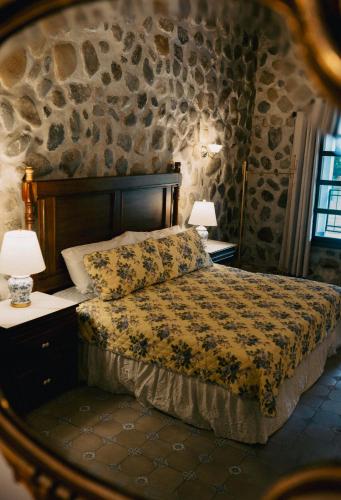 a bedroom with a bed and a stone wall at Hotel Boutique El Rosario in Teapa