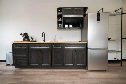 a kitchen with a white refrigerator and wooden cabinets at The Library @TheMillRowsSuites in New Glasgow