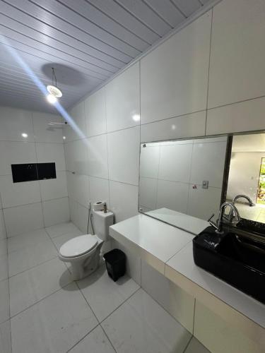 a white bathroom with a toilet and a sink at Espaço massagueira in Marechal Deodoro