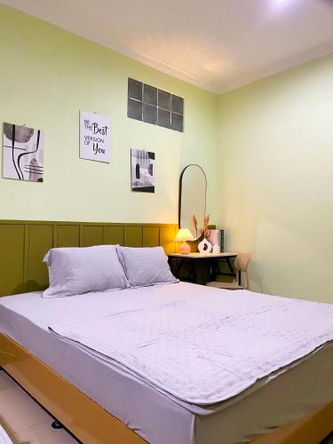 a bedroom with a bed and a desk with a sign on the wall at Bandung CoStay in Bandung