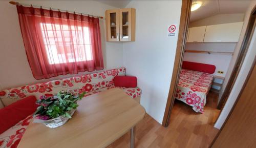 una pequeña sala de estar con mesa y sofá en Camping Norina, en Pesaro