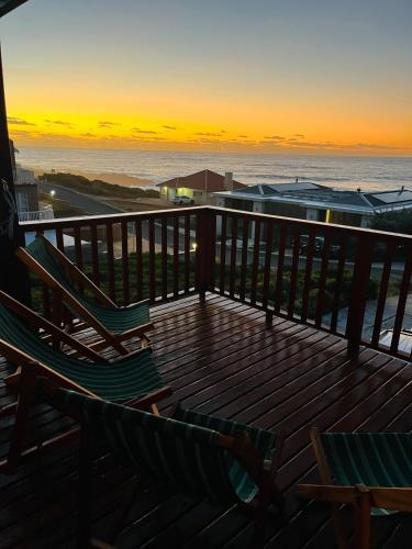 a deck with two chairs and the ocean at sunset at 360onSea in De Kelders