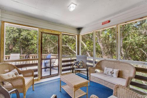 a screened in porch with wicker furniture and windows at 2002 - Hidden Aweigh in Sanderling