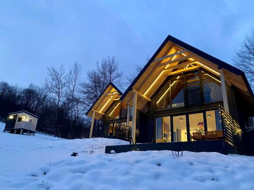 een huis in de sneeuw met lichten aan bij elements - Solina, z sauną in Solina