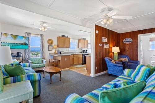 een woonkamer met blauwe banken en een keuken bij 4020 - Gardners Hut in Kitty Hawk Beach