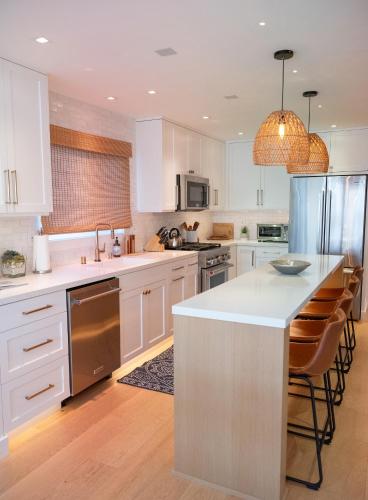 a kitchen with white cabinets and a white counter top at Luxe Harbor View 3BR - Rooftop Deck, Steps to Sand - Rare AC & Garage Parking in Newport Beach