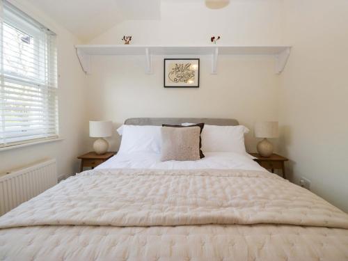 a bedroom with a large white bed with two lamps at Tram Lane Cottage in Carnforth