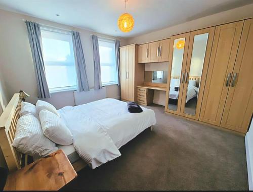 a bedroom with a large white bed and a mirror at Roomy, comfortable Greater London home, sleeps 8 in Thornton Heath
