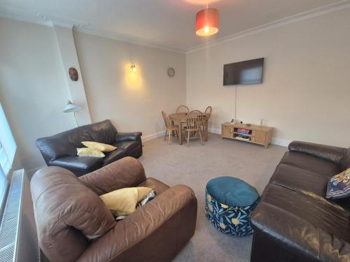 a living room with two leather couches and a table at Roomy, comfortable Greater London home, sleeps 8 in Thornton Heath