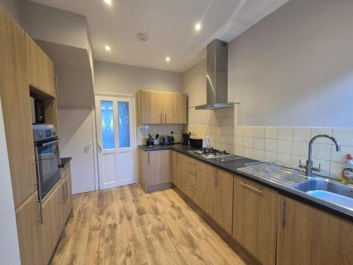 a large kitchen with wooden cabinets and a sink at Roomy, comfortable Greater London home, sleeps 8 in Thornton Heath