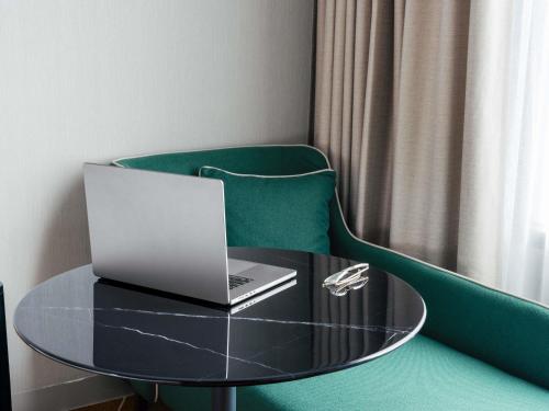 a table with a laptop on a green chair at Mantra Melbourne Airport in Melbourne