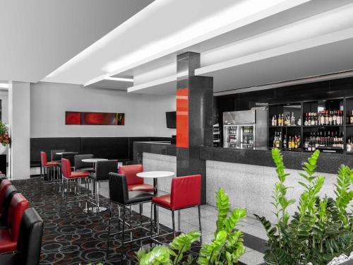 a bar with red chairs and tables in a room at Mantra Melbourne Airport in Melbourne