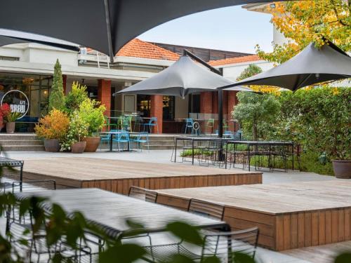 een terras met tafels, stoelen en parasols bij Peppers Gallery Hotel in Canberra