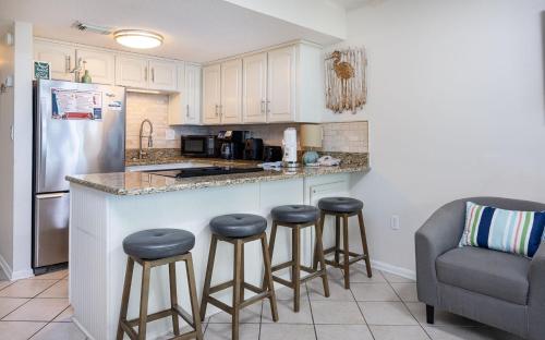 a kitchen with bar stools and a counter with a refrigerator at Island Winds West 777 in Gulf Shores
