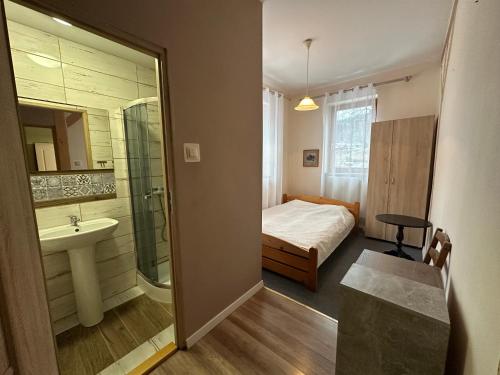 a bedroom with a bed and a bathroom with a sink at Pod Kasztanem in Wisła