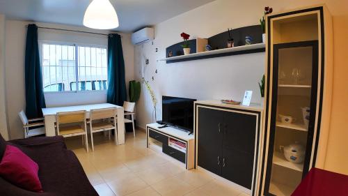 ein Wohnzimmer mit einem Tisch und einem TV in einem Zimmer in der Unterkunft Apartalux Clara Campoamor in Carboneras
