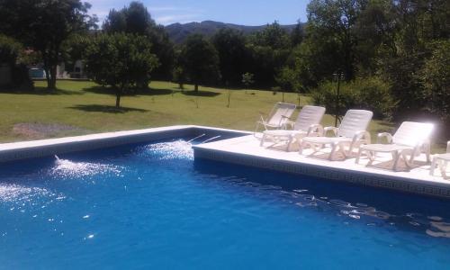 een groep witte stoelen naast een zwembad bij Casa Punilla in Valle Hermoso
