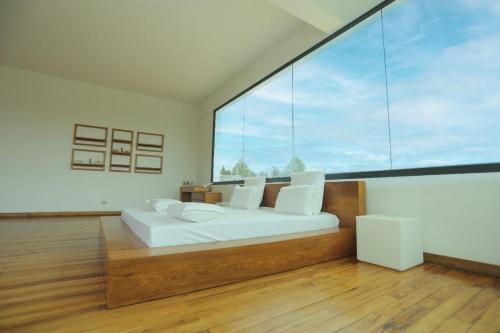 a bedroom with a white bed and a large window at Ricefield Valley in Mandriankeniheny