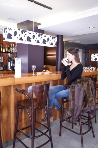 a woman sitting at a bar in a restaurant at Hotel MU in La Cortinada