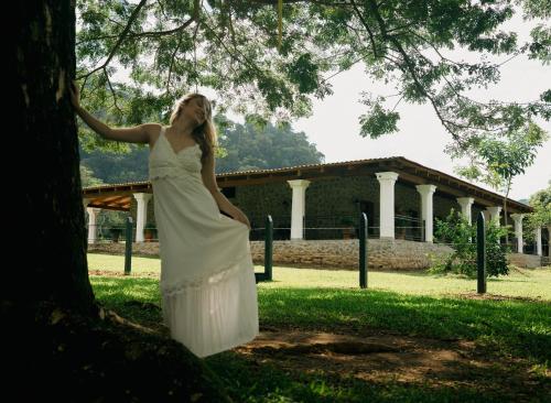 een vrouw in een witte jurk die tegen een boom leunt bij Hotel Boutique El Rosario in Teapa