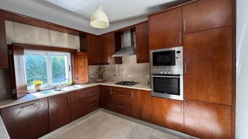 a large kitchen with wooden cabinets and a window at Pouso Du'Vagar in Cuba