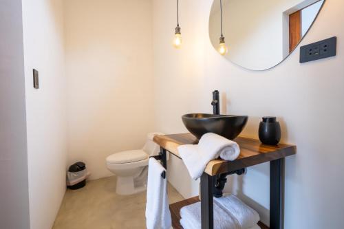 een badkamer met een wastafel, een toilet en een spiegel bij Bahia Selvatica Lodge in Uvita