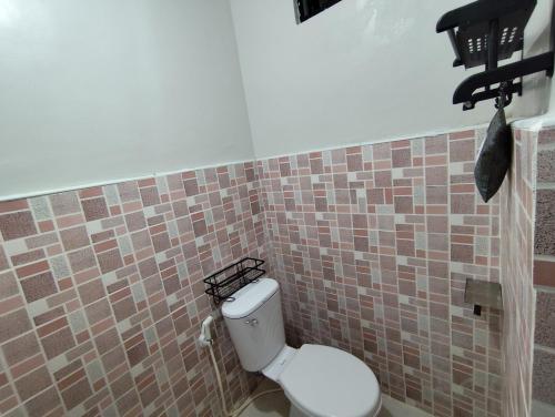 a bathroom with a toilet in a tiled wall at Lorna's Home in Panglao Island