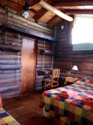 a bedroom with a bed in a log cabin at Cabaña Alcione in Capilla del Monte