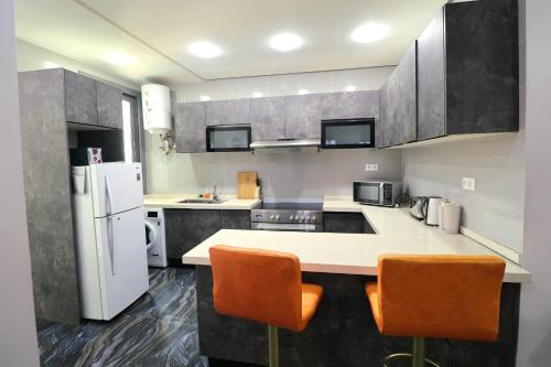 una cucina con un frigorifero bianco e sedie arancioni di NOVA PREMIUM ROOMs a Dakar