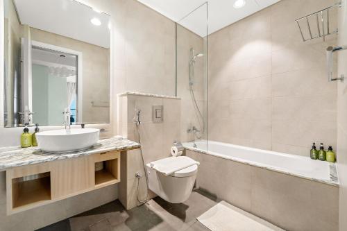 een badkamer met een wastafel, een toilet en een badkuip bij VayK - Spacious 2BR Inside Hotel in Dubai