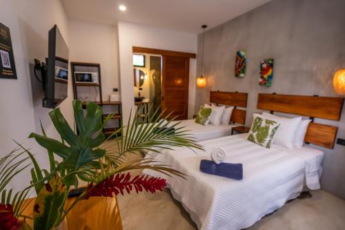 een slaapkamer met 2 bedden en een plant bij Bahia Selvatica Lodge in Uvita