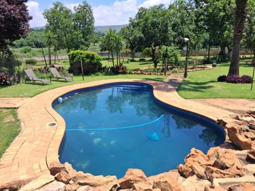 una piscina con un percorso in mattoni intorno ad essa di Greenstone Guesthouse a Muldersdrift