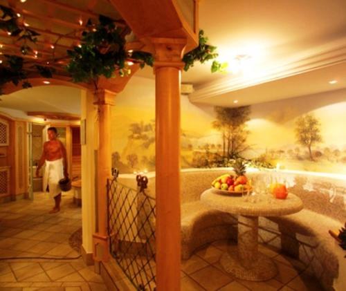a man walking down a hallway with a table of fruit at Hotel Reipertingerhof in Brunico