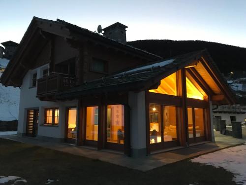 a house with large windows and a roof at Chalet Taulei tra Bormio e Livigno in Valdidentro