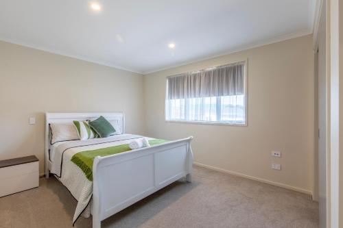 una camera da letto bianca con un letto e una finestra di Stylish apartment Whanganui a Whanganui