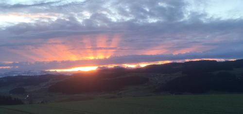 a sunset over a field with the sun setting at Bio Garni Möschberg in Grosshochstetten