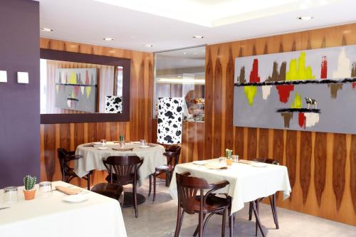 a restaurant with white tables and chairs and wooden walls at Hotel MU in La Cortinada
