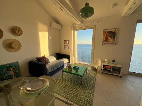 een woonkamer met een bank en uitzicht op de oceaan bij Casa Favelas, Vue Mer, plages et Monaco à pieds in Cap d'Ail
