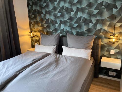 een slaapkamer met een wit bed en een geometrische muur bij Platzhirsch-bei-der-Purpurbuche in Bad Harzburg