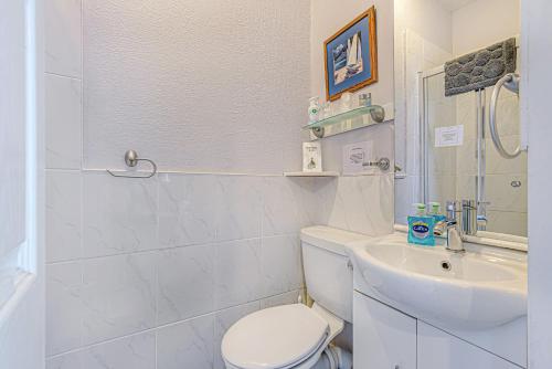 a white bathroom with a toilet and a sink at Capritia Guest House in Dartmouth
