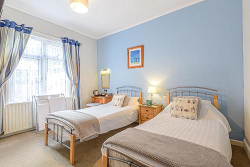 two beds in a bedroom with blue walls at Capritia Guest House in Dartmouth