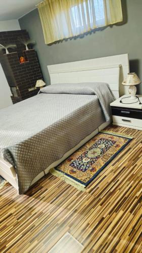 ein Schlafzimmer mit einem Bett und einem Teppich auf dem Boden in der Unterkunft Casa Sulfina in Radoşi