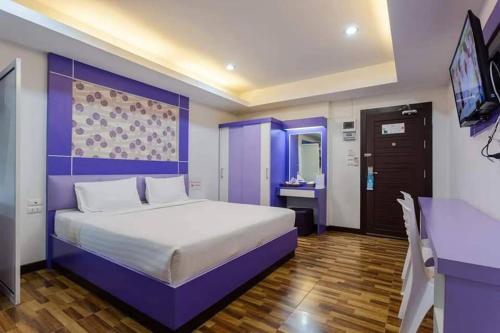 a bedroom with a large bed and a tv at The Ring Residence in Sathani Hat Yai