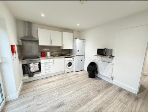 a kitchen with white cabinets and a wooden floor at Moor Layover Heathrow - Cozy Crew Stay - 10 min to Airport in Harmondsworth