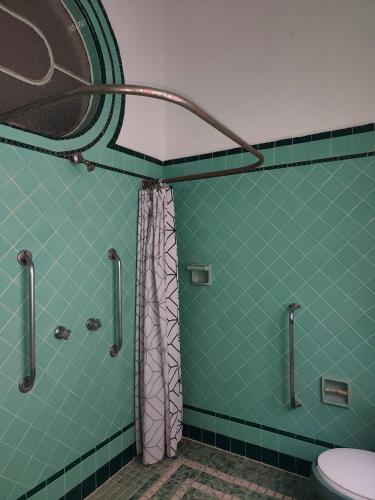 a green tiled bathroom with a shower and a toilet at Hospedaje en habitación casa colonial centro histórico Puebla in Puebla