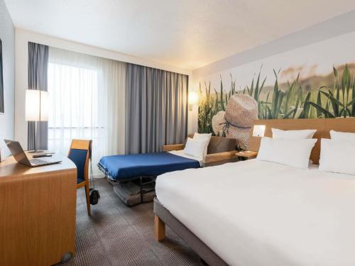 een hotelkamer met een bed en een bureau bij Novotel Paris Est in Bagnolet