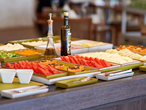 a table filled with different types of food and a bottle of wine at Novotel Sao Jose dos Campos in São José dos Campos